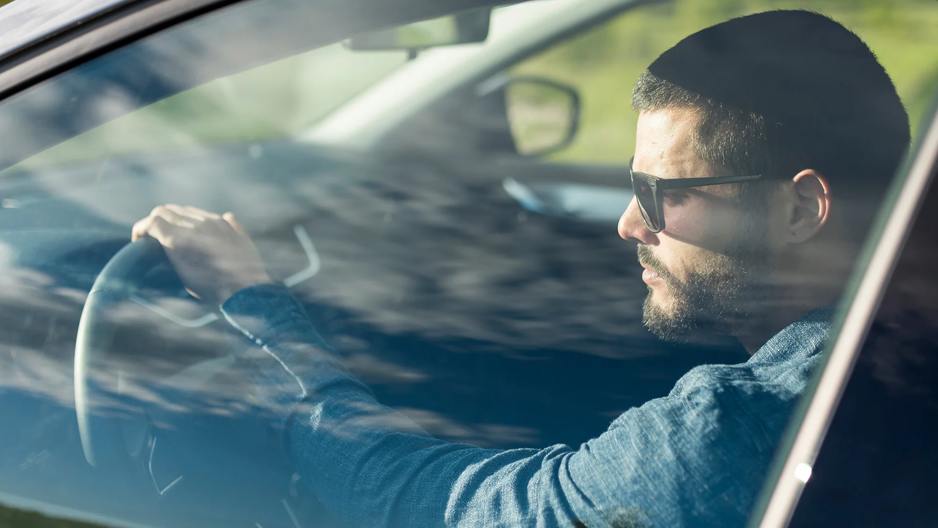 Male with sunglasses driving car